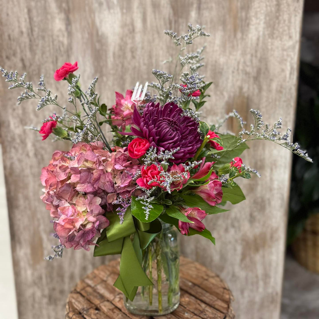 Bouquet of flowers in a clear vase on a wooden surface with a rustic background