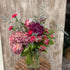 Bouquet of flowers in a clear vase on a wooden surface with a rustic background