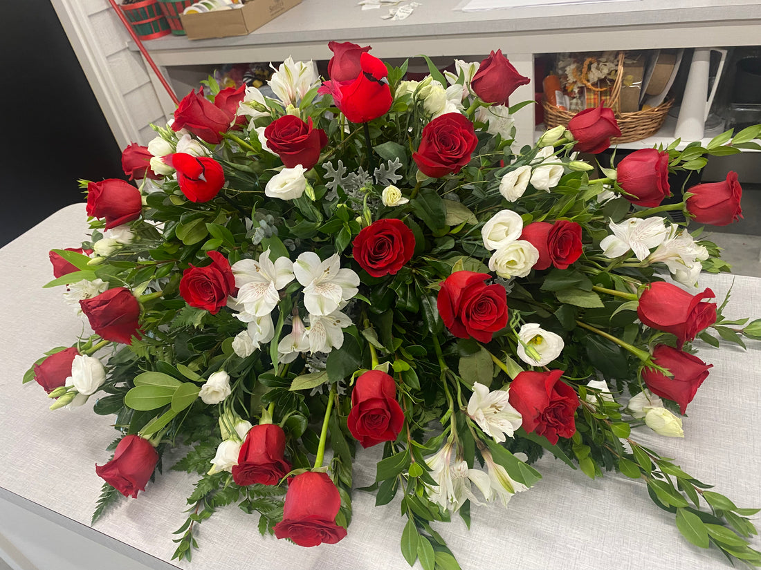 Red and white funeral casket spray with fresh roses, lisanthus and greenery by Smitty’s Floral in Fort Dodge, Iowa.