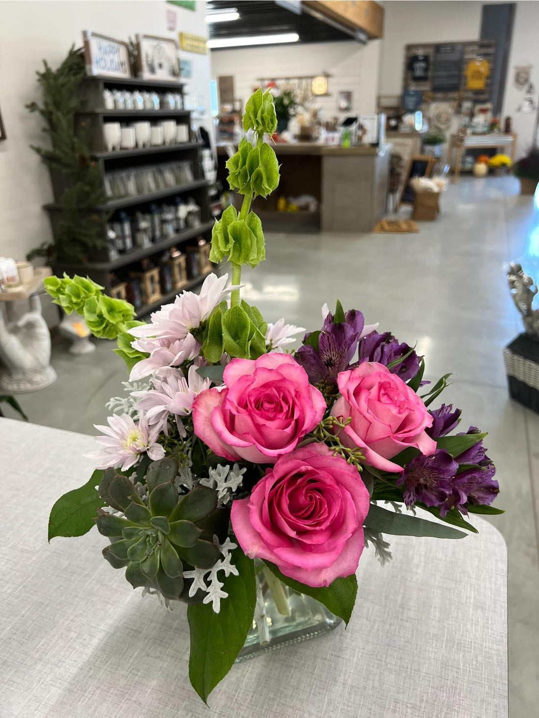 Bouquet of pink and purple flowers in a glass vase on a table.