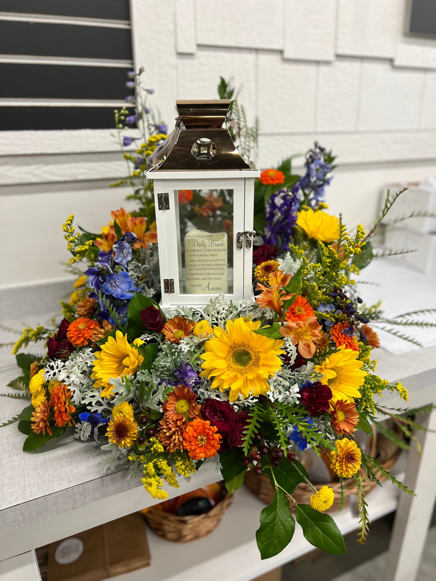 Elegant sympathy floral arrangement designed around a cremation urn with fresh flowers and greenery.